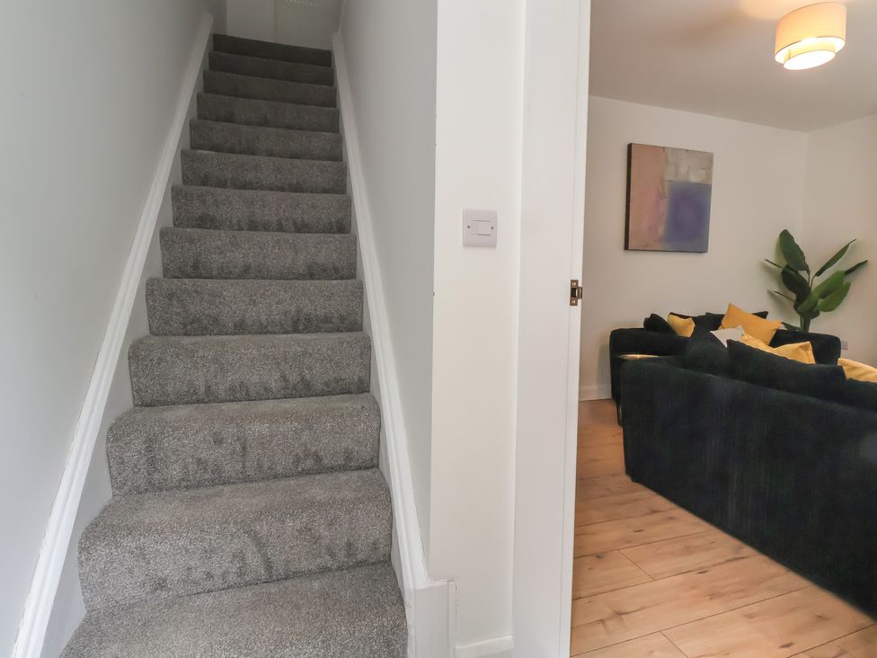 Stairs leading to living room with sofa and artwork at 5 Marsh Lane in Flint