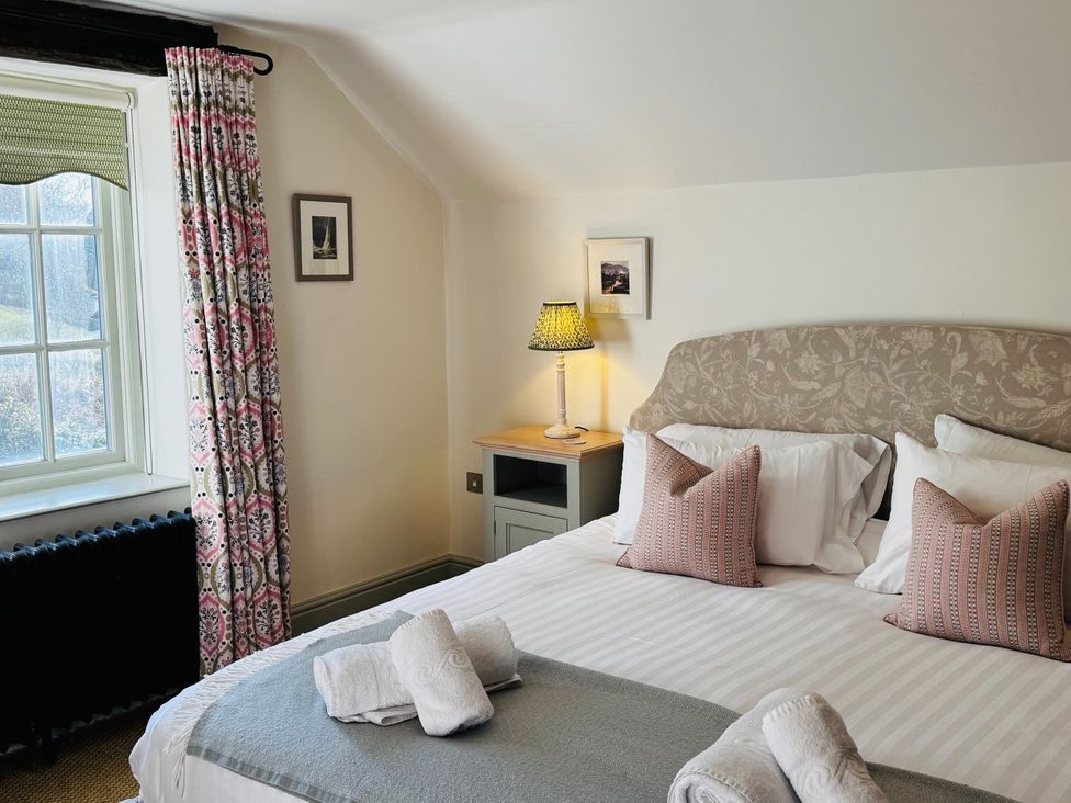 A bedroom with a bed, pillows, lamp, and window at Stone Arthur Cottage in Grasmere