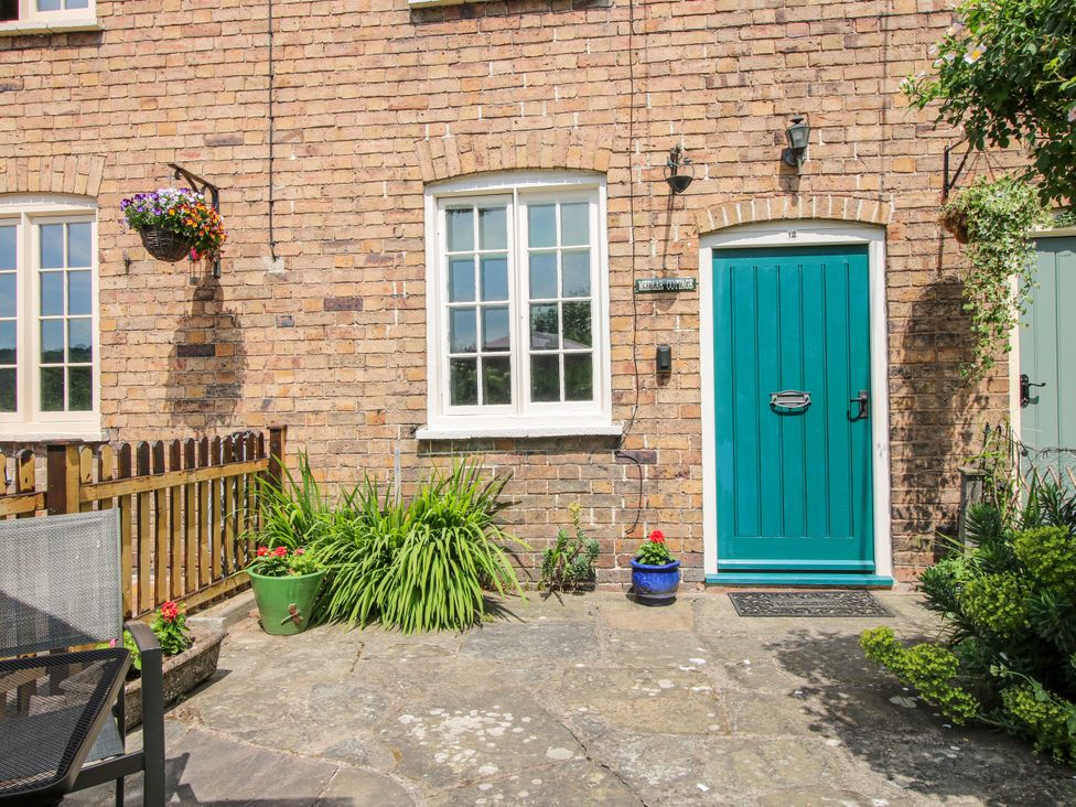 An outdoor area with a green door and a brick wall at Medlar Cottage Ironbridge