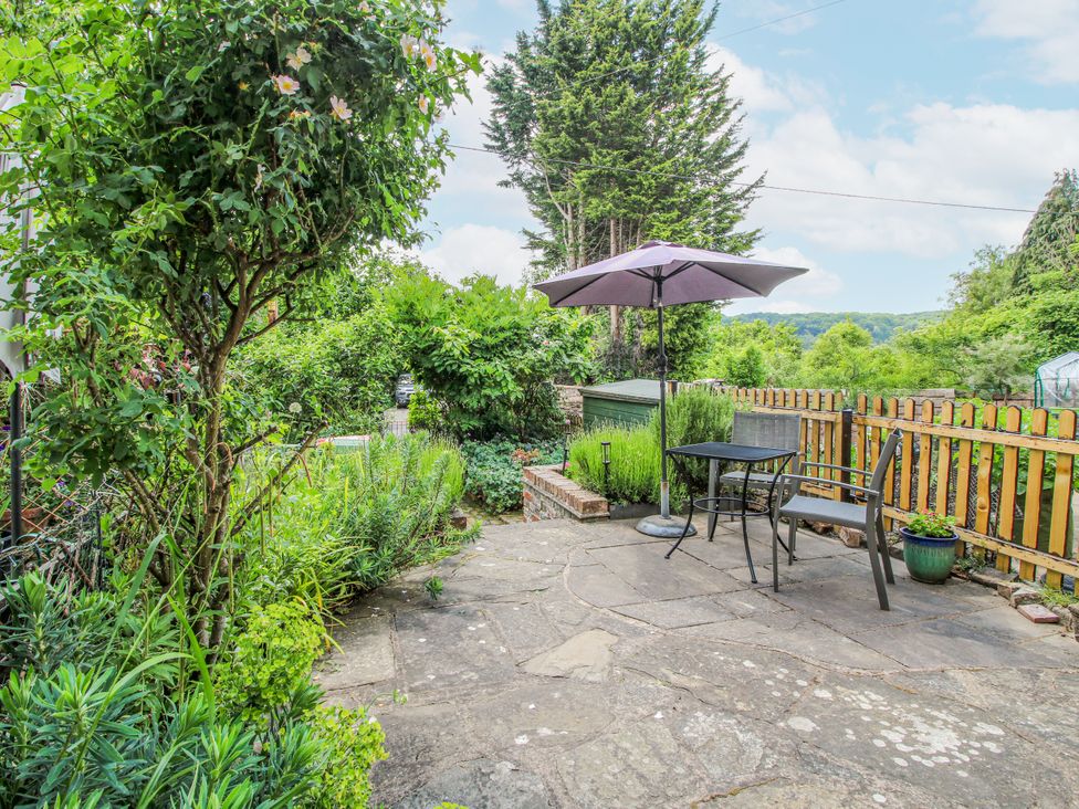 A garden with table and chairs under an umbrella at Medlar Cottage Ironbridge