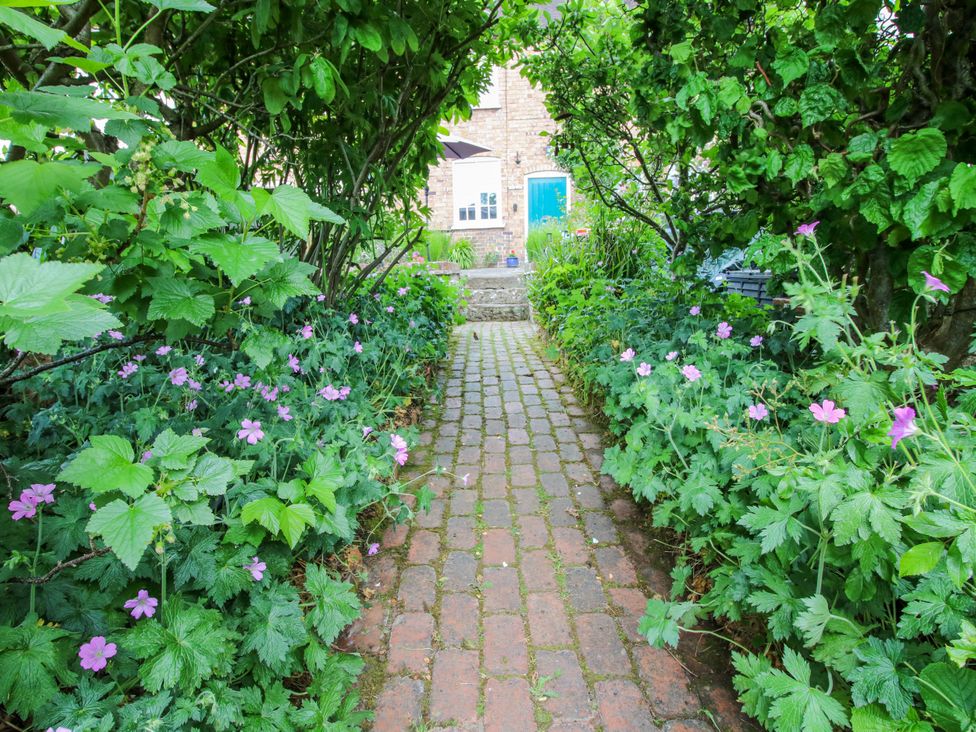 A pathway surrounded by flowers leading to a door at Medlar Cottage in Ironbridge
