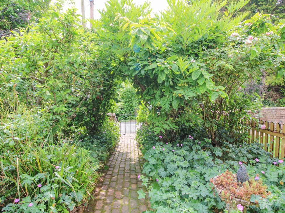 A garden pathway with plants and a gate at Medlar Cottage in Ironbridge
