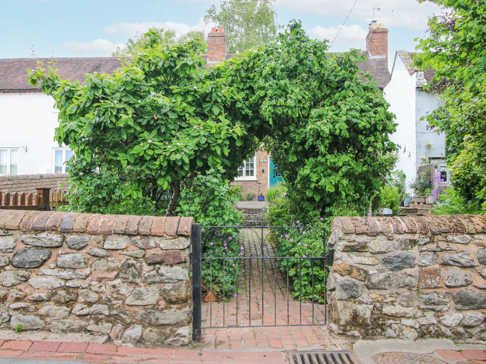 A garden pathway with a stone wall and gate at Medlar Cottage in Ironbridge