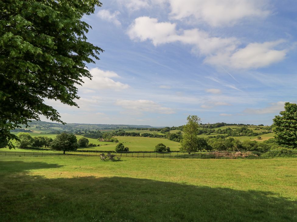 A grassy field with trees and outdoor chairs under a partly cloudy sky at Blue Bell in Colerne