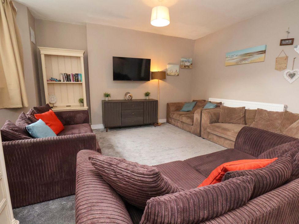 A living room with a television and sofa arrangements at The Corner House in Scarborough