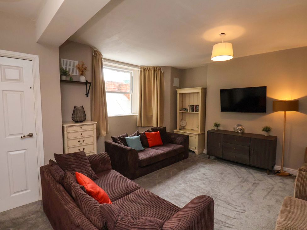 A living room with sofas and a television at The Corner House in Scarborough