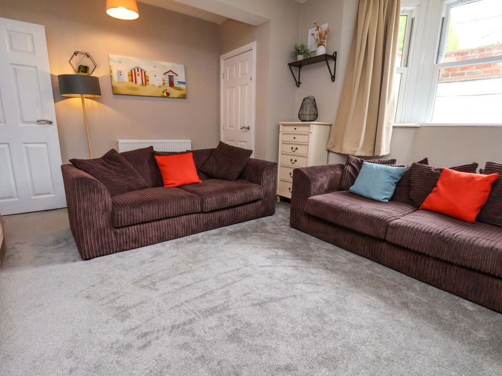 A living room with sofas and a lamp at The Corner House in Scarborough