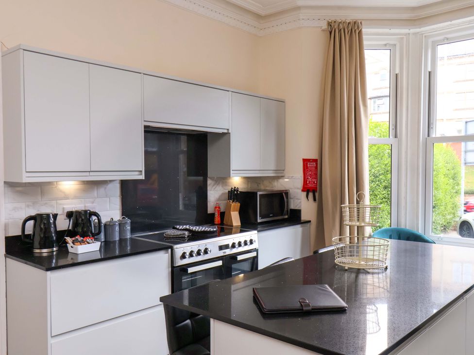 A kitchen with cabinets and appliances including a stove and microwave at The Corner House Scarborough