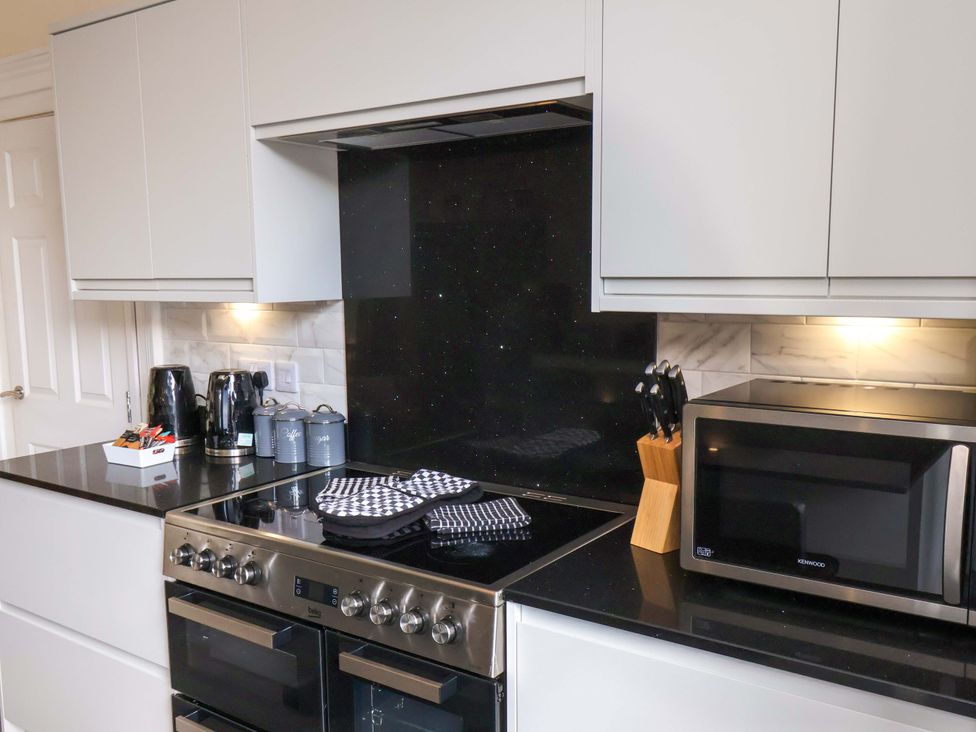 A kitchen with an oven, microwave, knives, and kettle at The Corner House in Scarborough