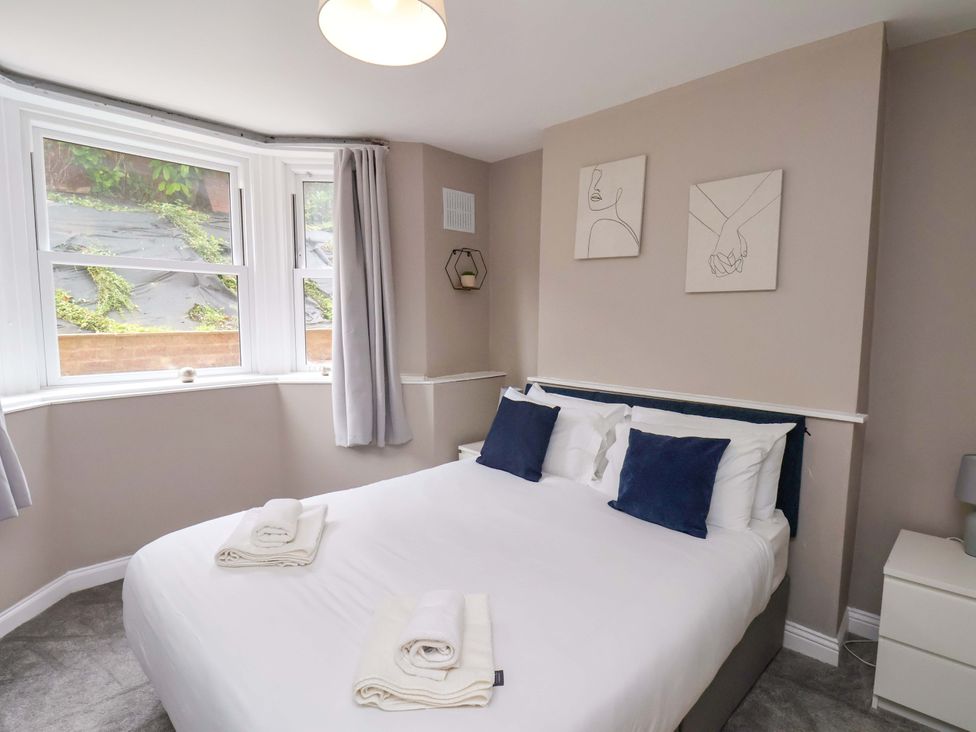 A bedroom with a bed and windows at The Corner House in Scarborough