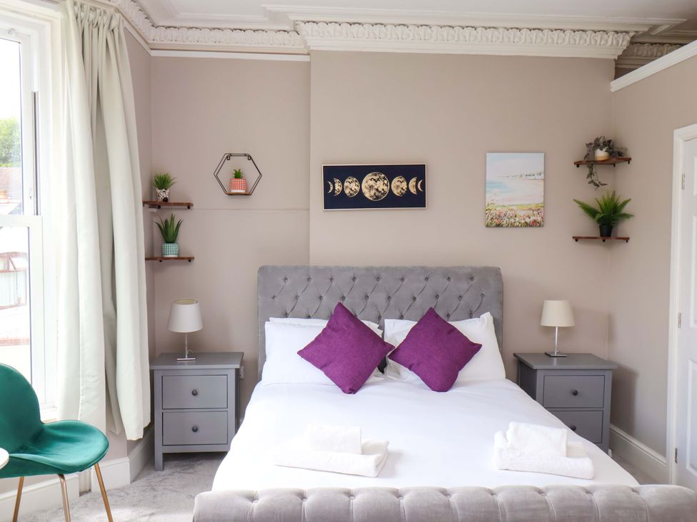 A bedroom with a bed and nightstands at The Corner House in Scarborough