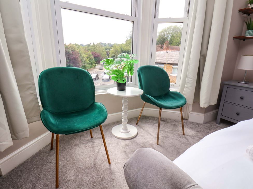 A sitting room with green chairs and a small table at The Corner House in Scarborough