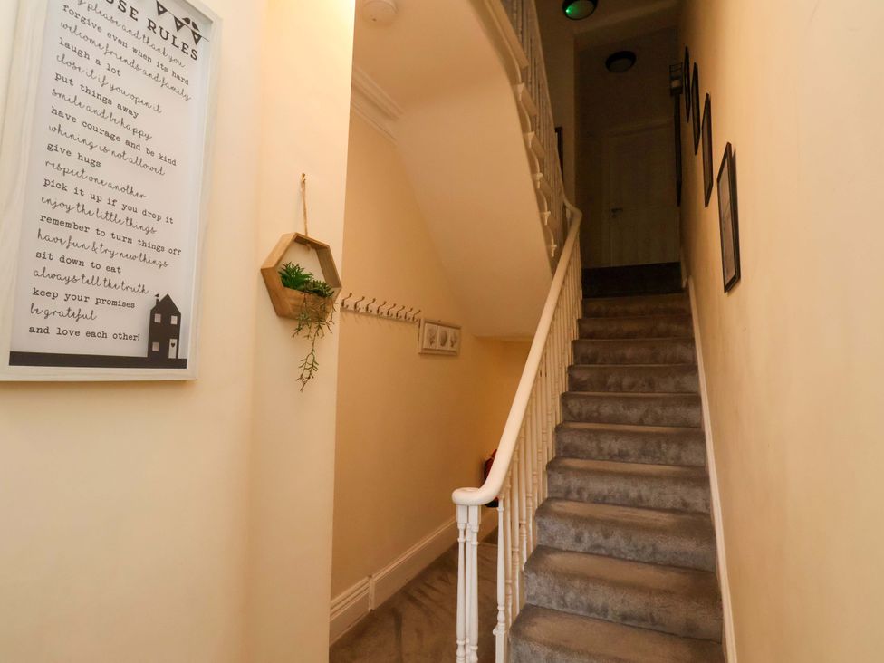 A hallway with a staircase and wall decor at The Corner House in Scarborough