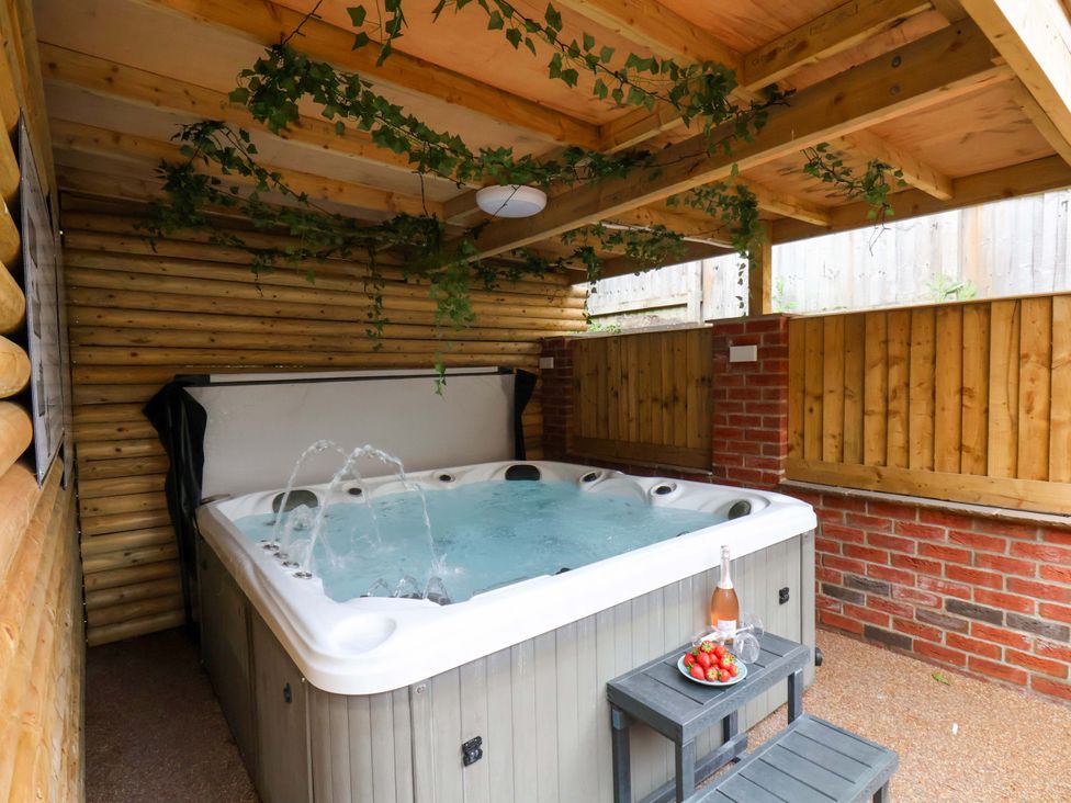 A hot tub with a wooden cover and stool in an outdoor area at The Corner House in Scarborough
