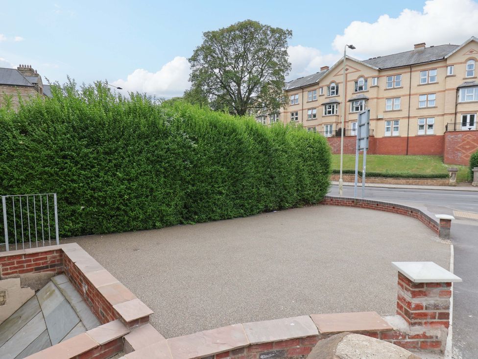 An outdoor area with a hedge and tree at The Corner House in Scarborough