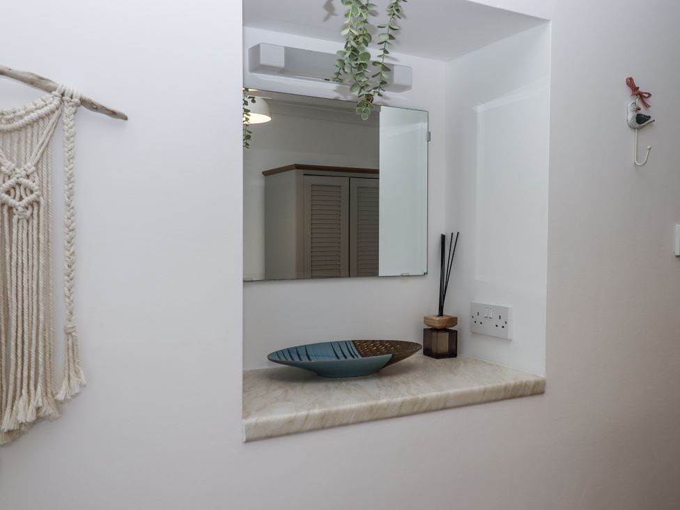 A bathroom with a shelf, mirror, and decorative elements at Driftwood in Dartmouth