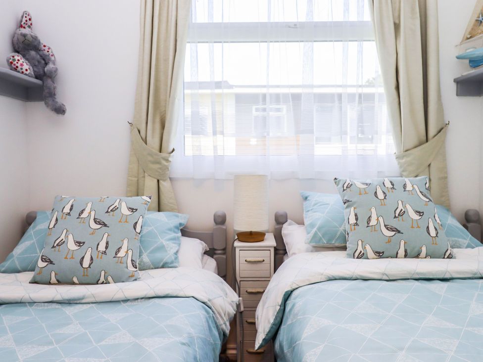 A bedroom with twin beds and decorative pillows at Driftwood in Dartmouth