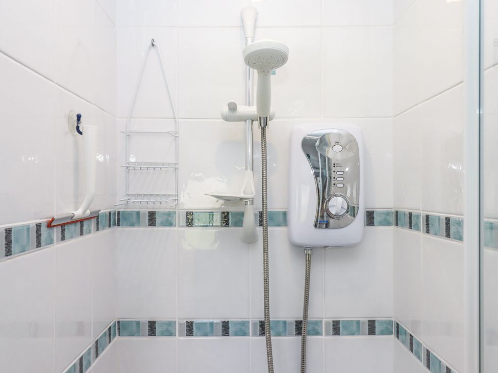 A shower with a water heater and storage rack at Driftwood in Dartmouth