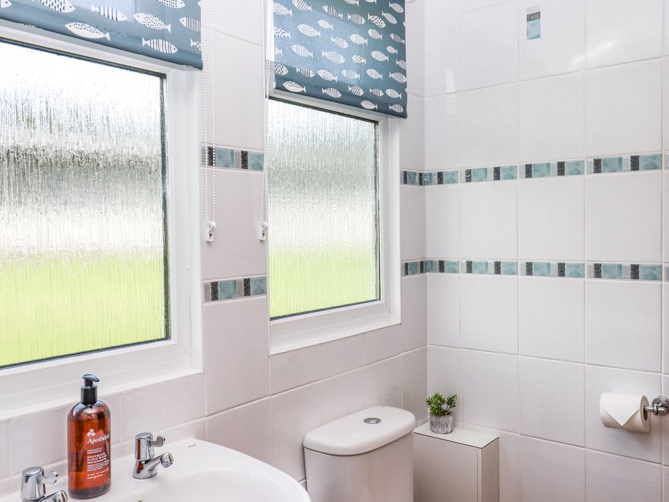 A bathroom featuring a sink, toilet, and windows at Driftwood in Dartmouth