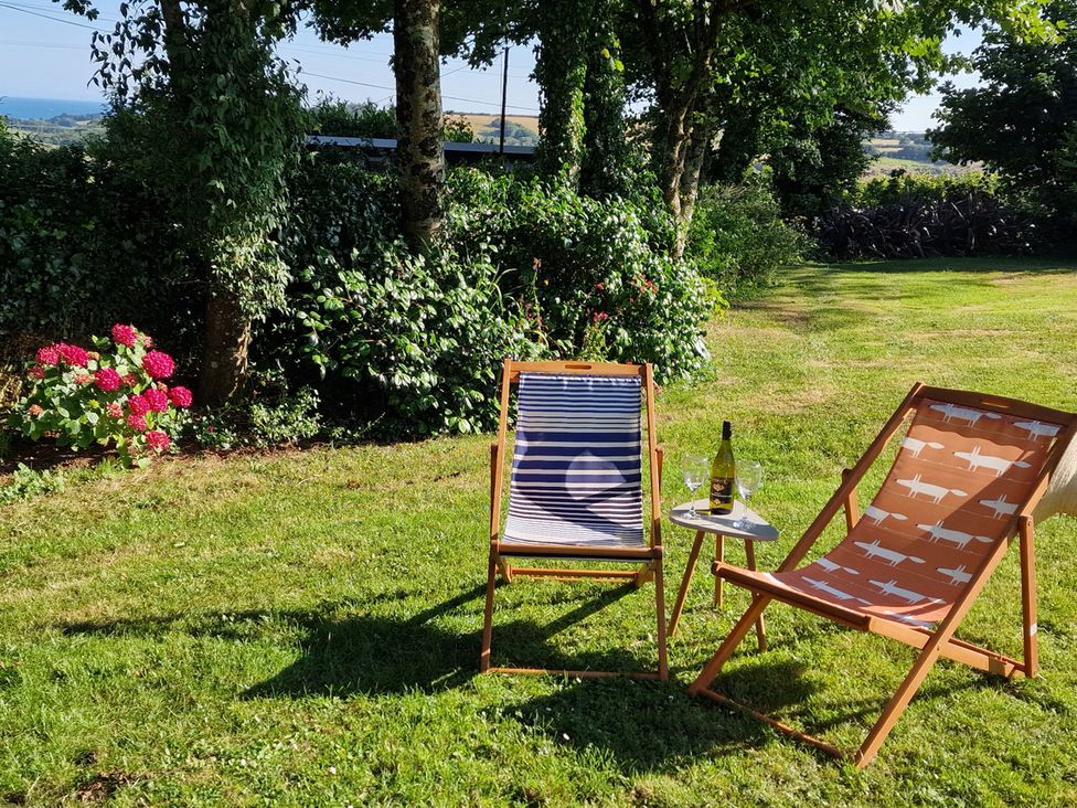 A garden with deck chairs and a table at Driftwood in Dartmouth