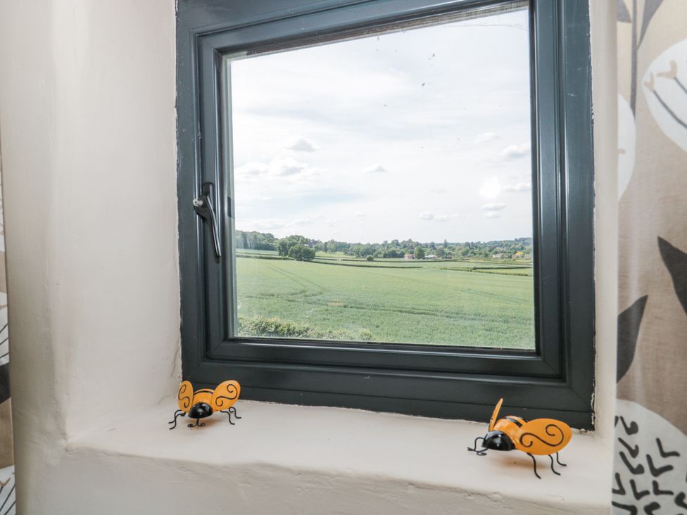 A window with decorative insects on the sill overlooking fields at The Bull Pen in Yeovil, Somerset
