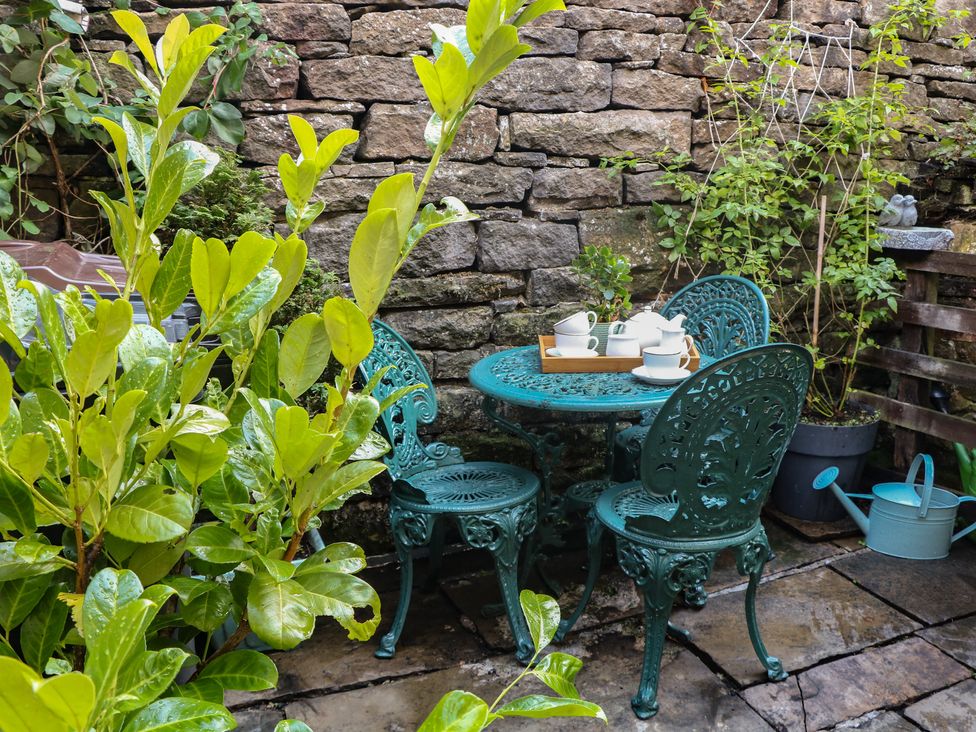 A garden with a table and chairs set for tea at Brook Cottage in Hayfield, High Peak