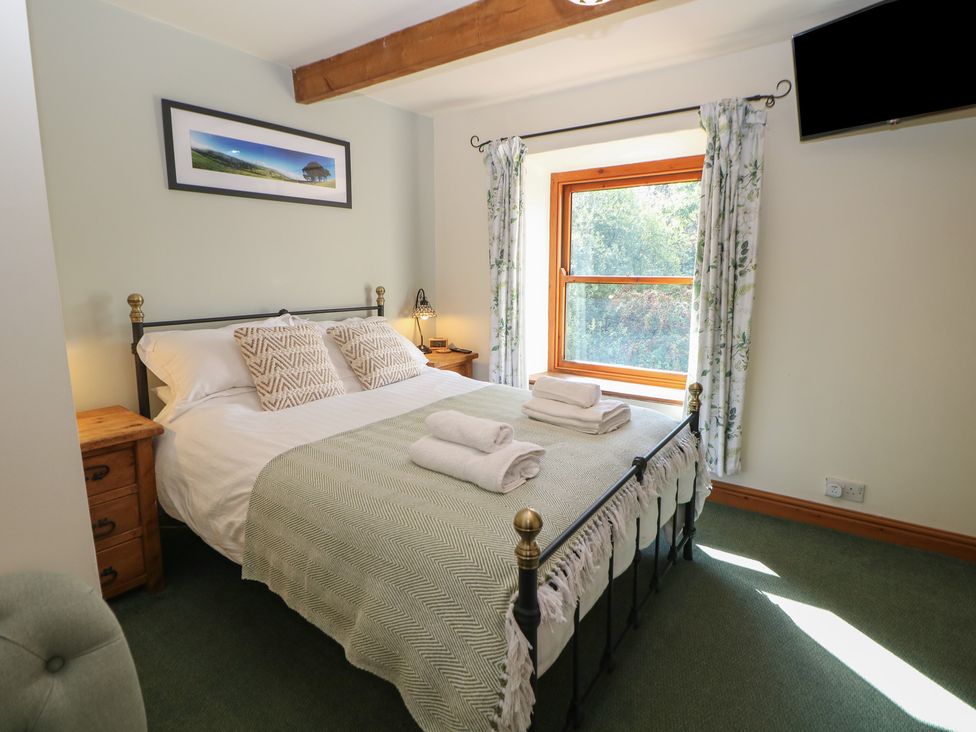 A bedroom with a bed and window at Brook Cottage in Hayfield, High Peak