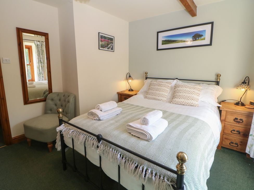 A bedroom with a bed and nightstand at Brook Cottage in Hayfield, High Peak