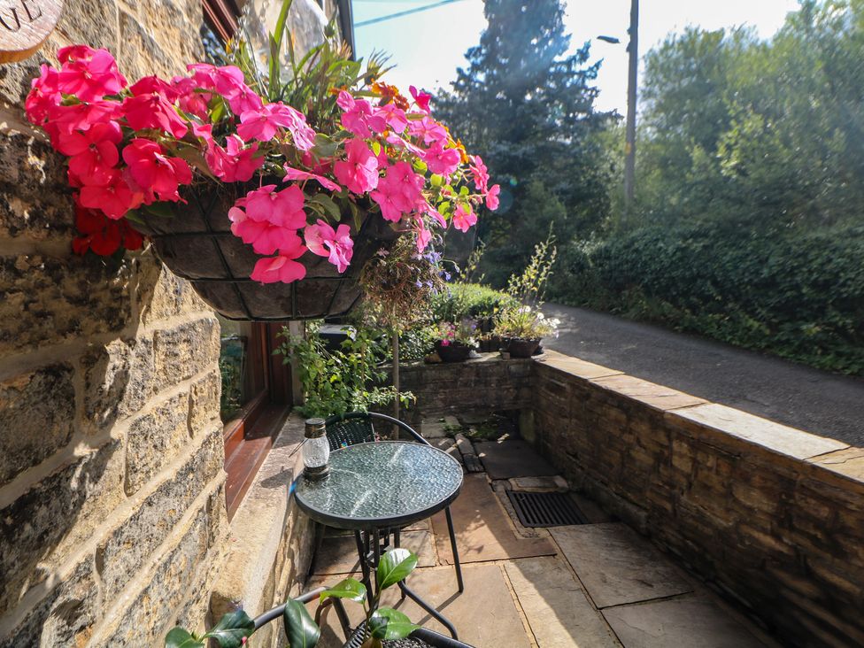 A patio area with a table and chair at Brook Cottage in Hayfield, High Peak