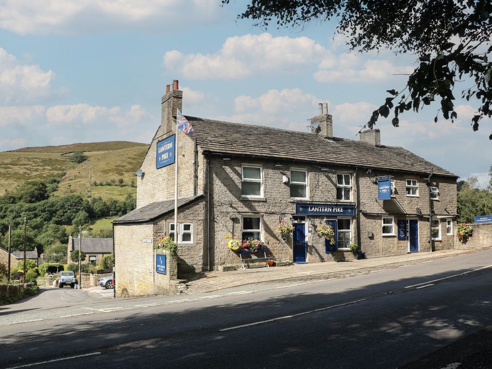 A building with a sign and flowers at Lantern Pike in Hayfield, High Peak