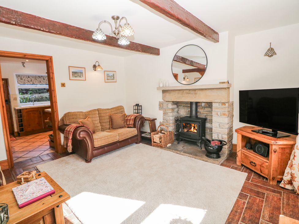 A living room with a sofa and fireplace at Brook Cottage in Hayfield, High Peak