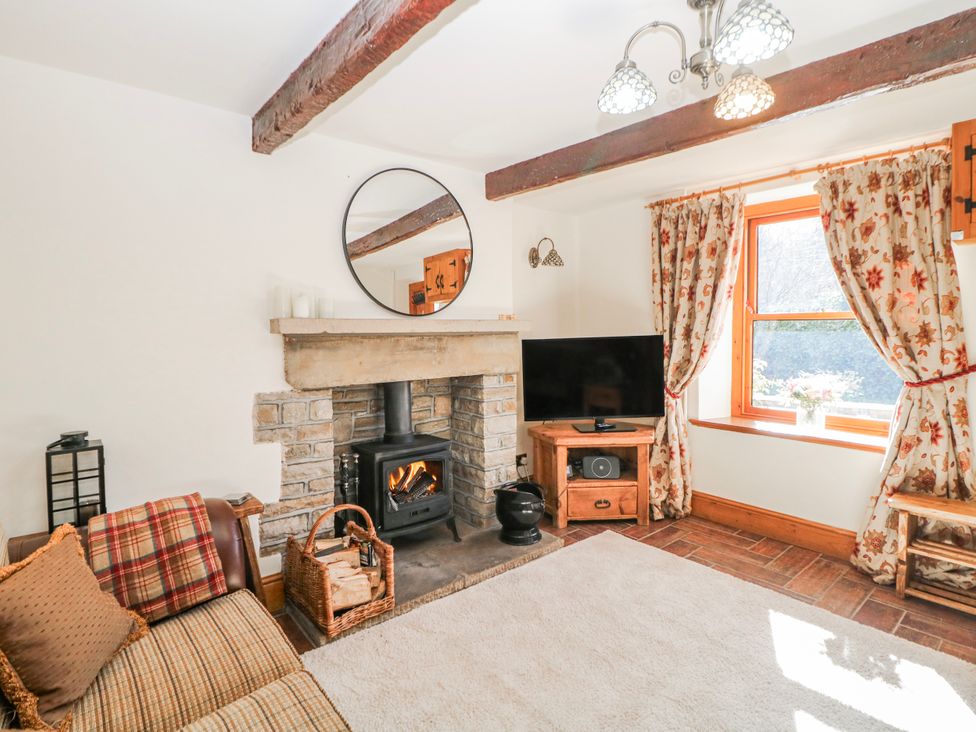 A living room with a fireplace and television at Brook Cottage, Hayfield, High Peak