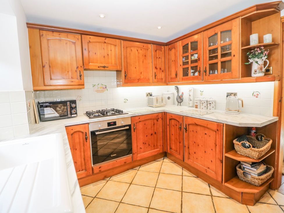 A kitchen with wooden cabinets and appliances at Brook Cottage in Hayfield, High Peak