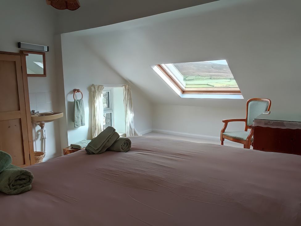A bedroom with a bed, towels, and a sink at Sally End in Ravenstonedale near Kirkby Stephen