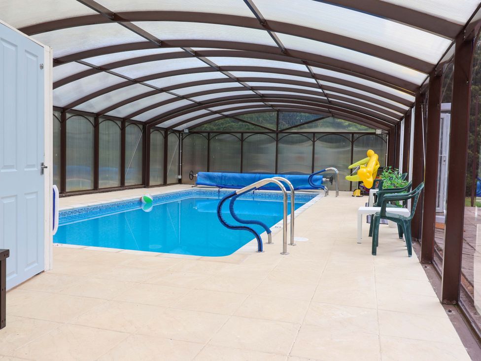 An indoor pool with a pool cover and chairs at Parkfields House Tittensor near Barlaston