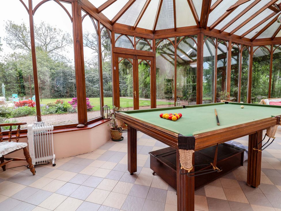 A conservatory with a billiard table and views of the garden at Parkfields House Tittensor near Barlaston