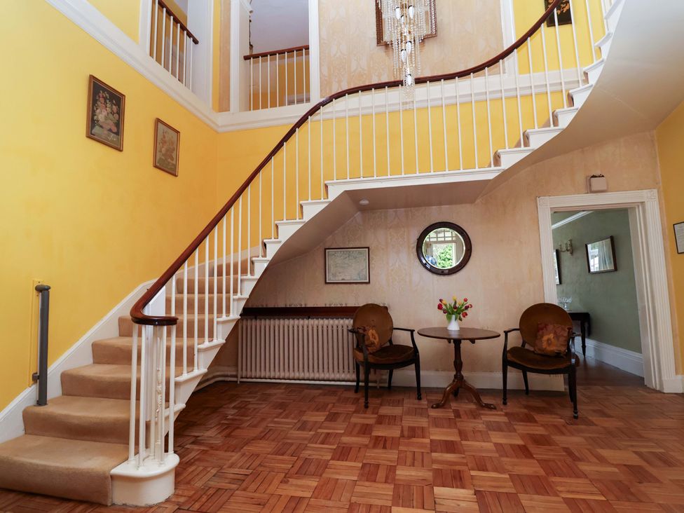 A hallway with a staircase, chairs, and a table at Parkfields House Tittensor near Barlaston