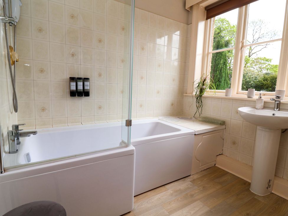 A bathroom with a bathtub, sink and toiletries at Parkfields House Tittensor near Barlaston
