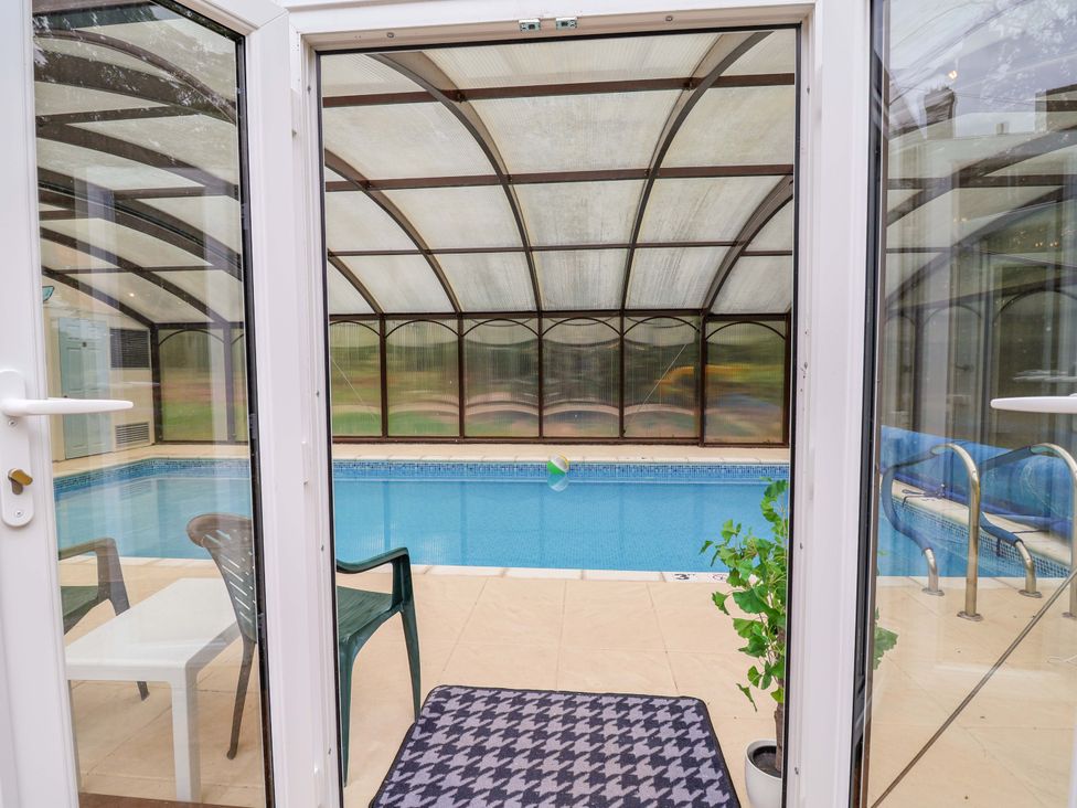A conservatory with an indoor pool and a chair at Parkfields House Tittensor near Barlaston