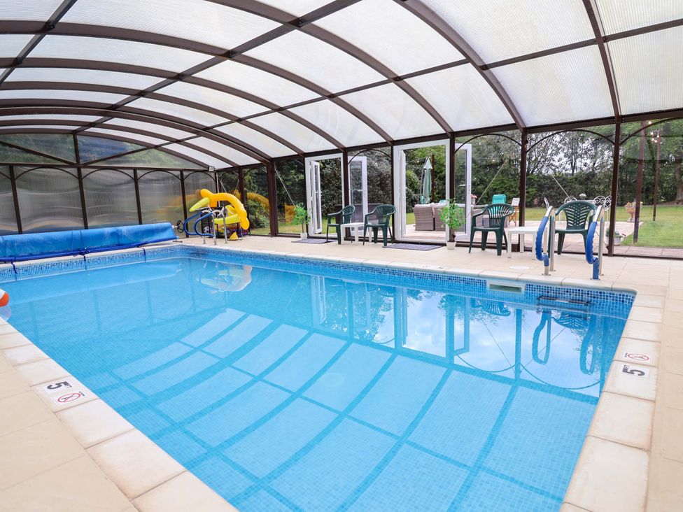 An indoor pool with a slide and seating area at Parkfields House Tittensor near Barlaston