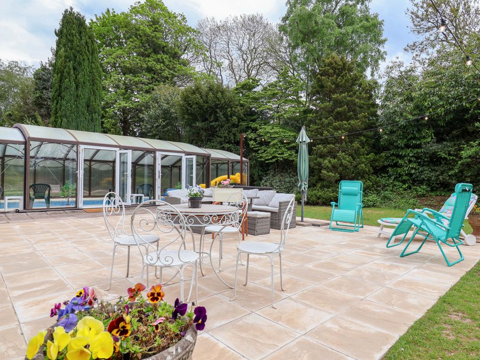 A garden with seating, pool enclosure, and flowers at Parkfields House Tittensor near Barlaston