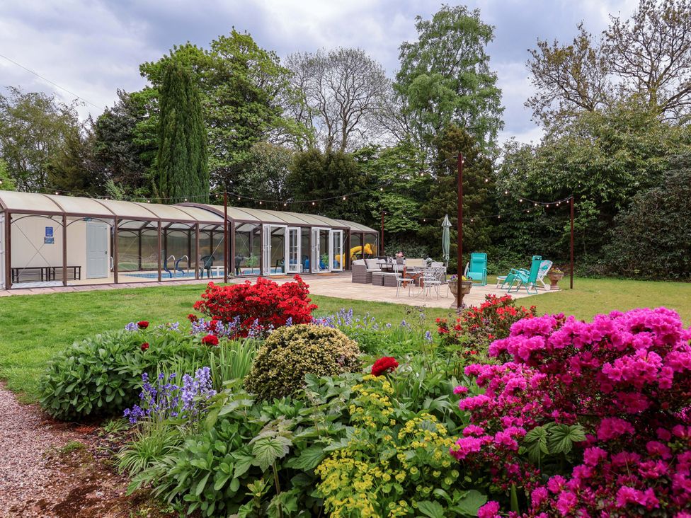 A garden with a pool enclosure and seating area at Parkfields House Tittensor near Barlaston