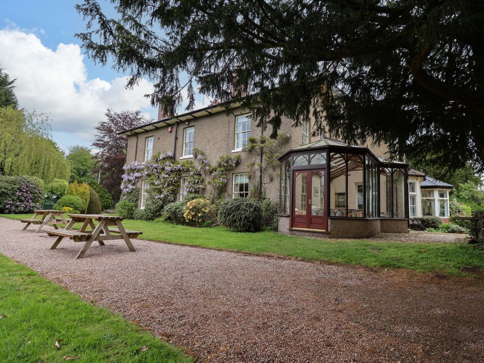 A house with a conservatory and benches in the garden at Parkfields House Tittensor near Barlaston
