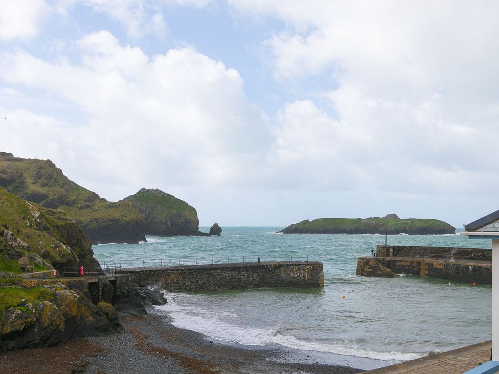A coastal view with a pier and rocky hills at Morwenna in Mullion