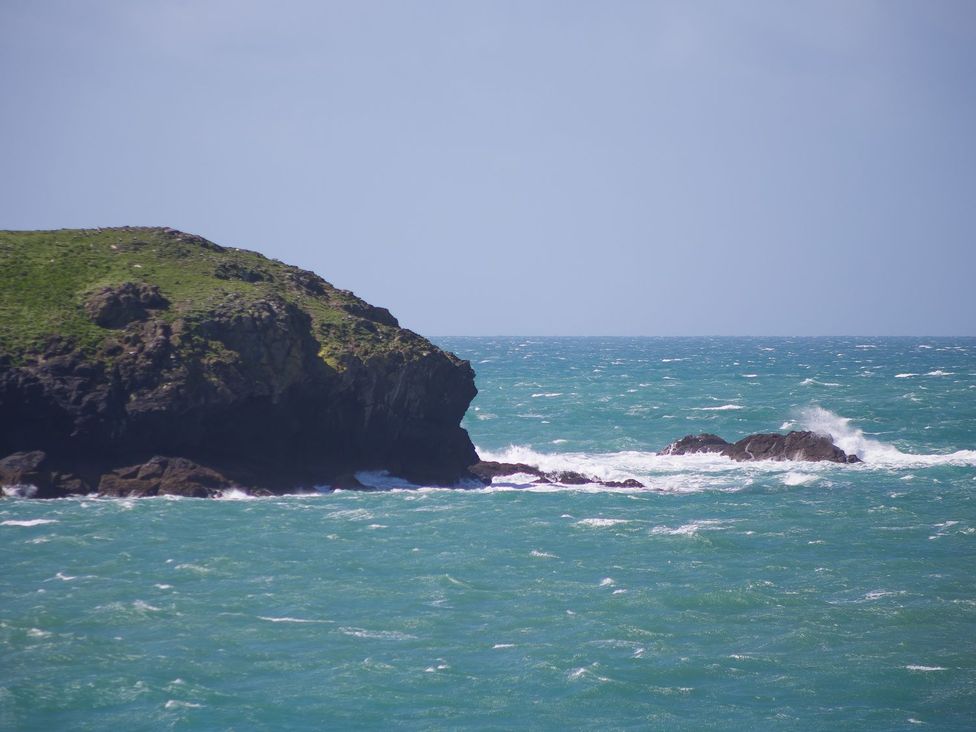 A rocky cliff beside the ocean with waves at Verity in Mullion