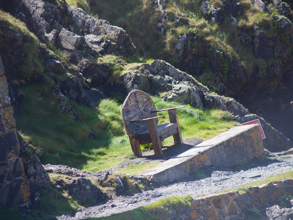 A chair next to rocks and grass at Daphne in Mullion