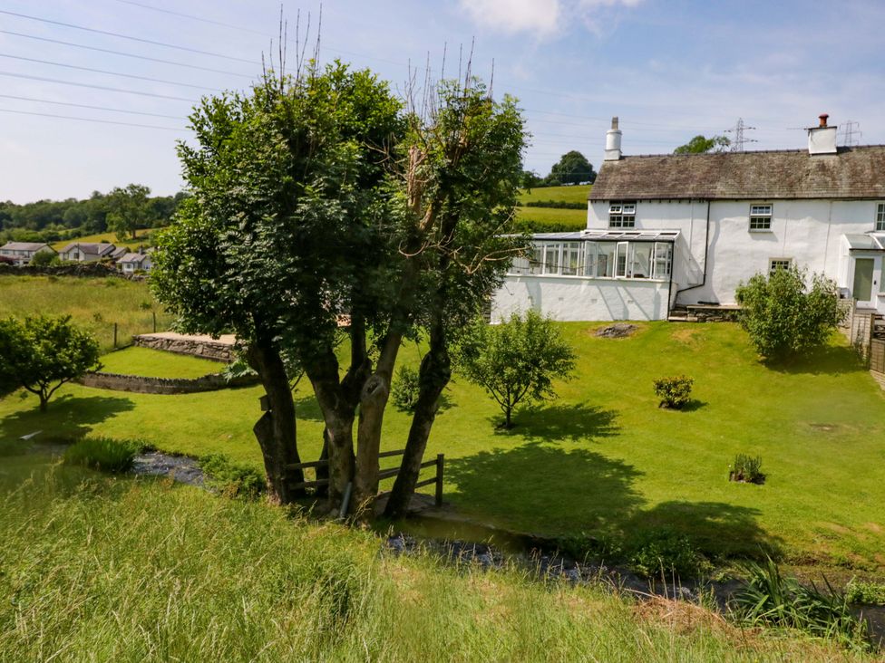 A house with trees and grass in an outdoor area at Burnbank Cottage Grange-Over-Sands
