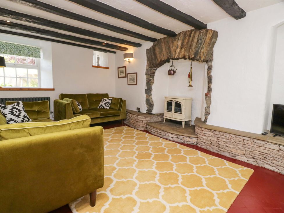 A living room with a fireplace and sofa at Burnbank Cottage in Grange-Over-Sands