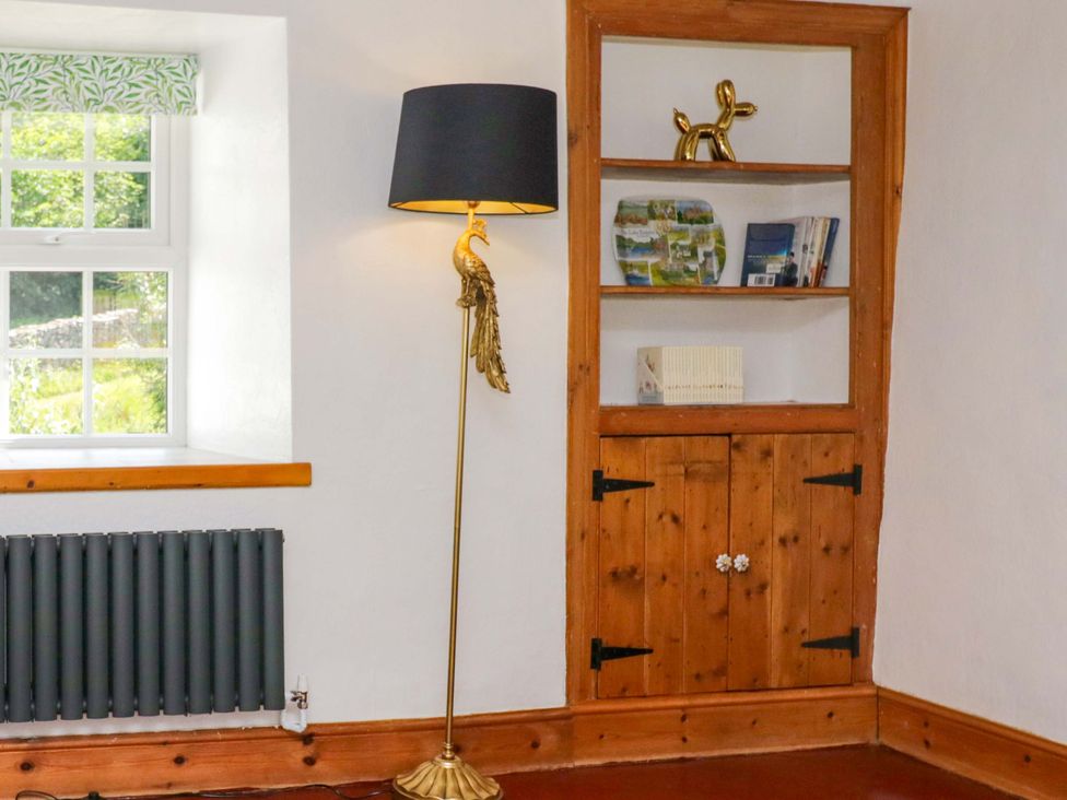 A living room with a window and a lamp at Burnbank Cottage in Grange-Over-Sands