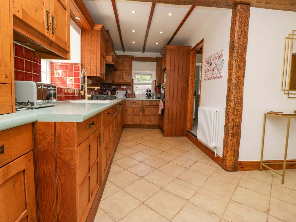 A kitchen with wooden cabinets and appliances at Burnbank Cottage in Grange-Over-Sands
